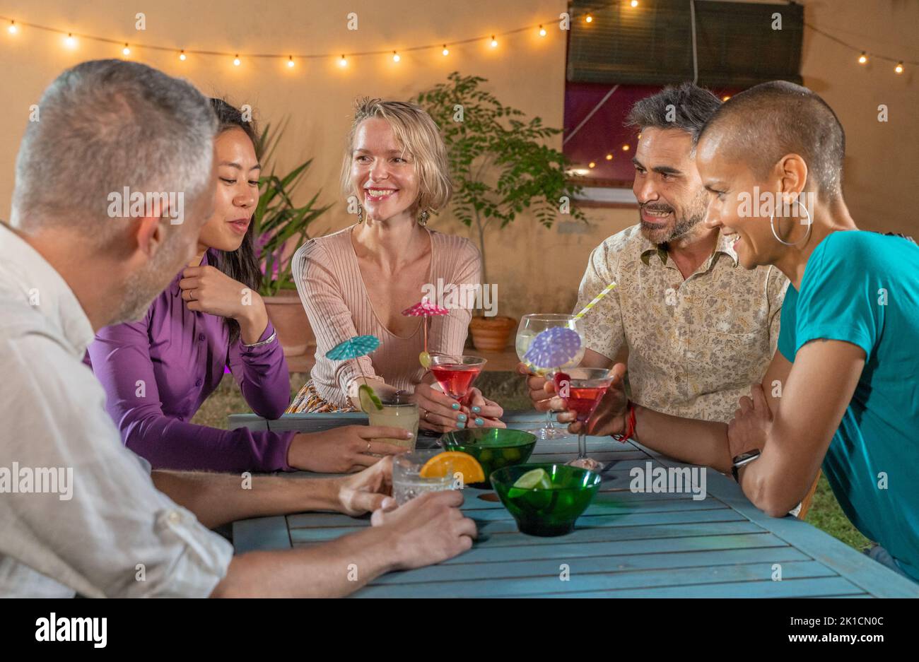 Groupe d'amis joyeux à la soirée de boire des cocktails et de s'amuser ensemble. Souriant, les gens apprécient la vie nocturne et boivent des boissons alcoolisées. Banque D'Images