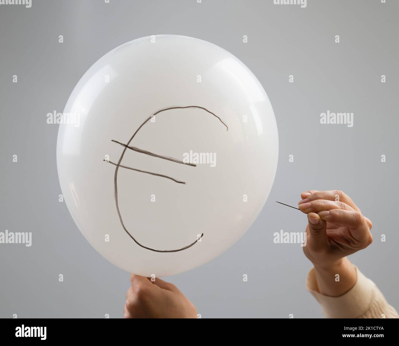 Une femme éclate avec une aiguille un ballon avec l'inscription euro. Banque D'Images