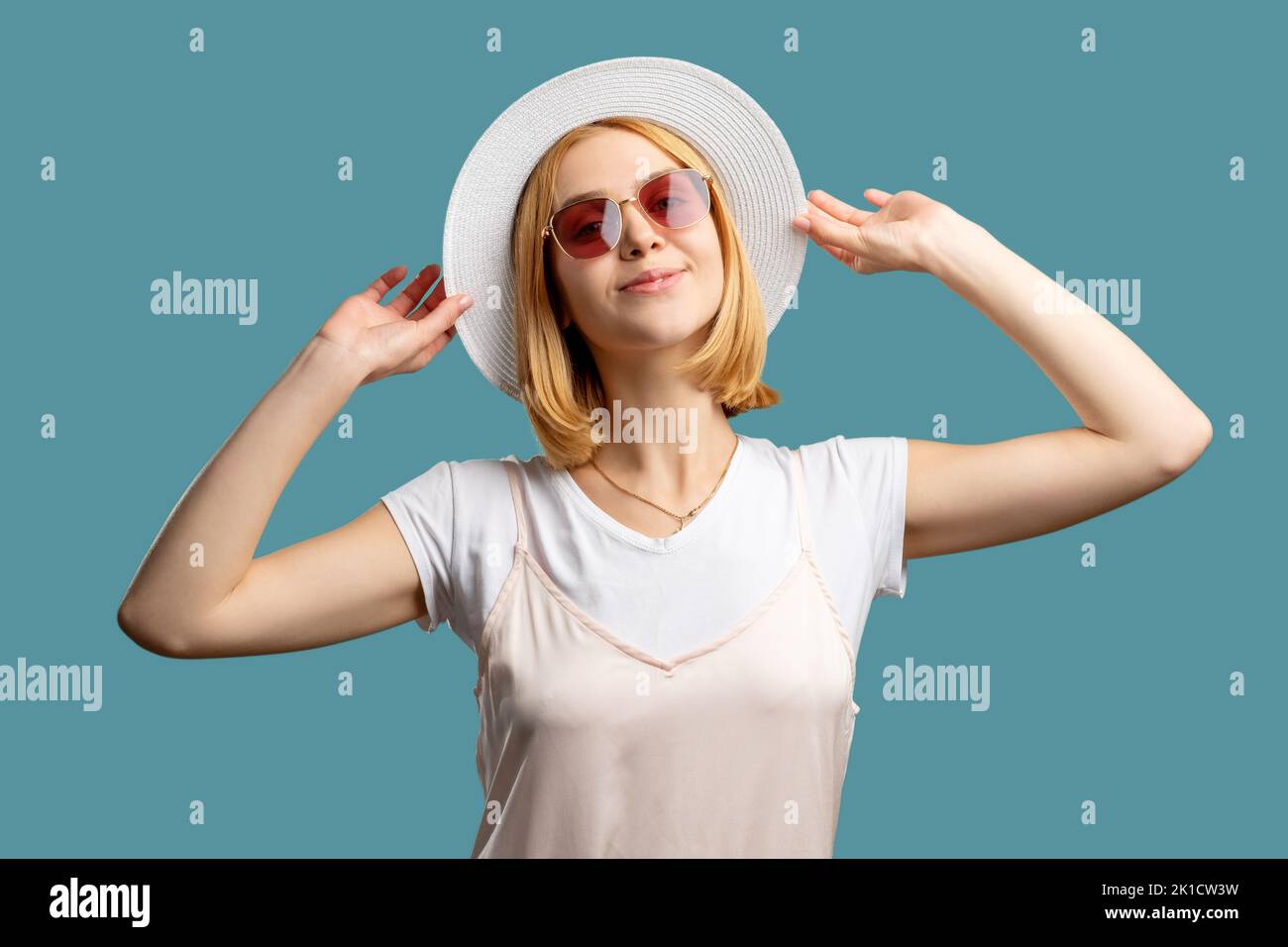 Accessoires de vacances. Voyage d'été. Bonne femme en costume blanc chapeau gitan et lunettes de soleil appréciant les vacances isolées sur bleu. Agence de voyages. Tête de lit tendance Banque D'Images