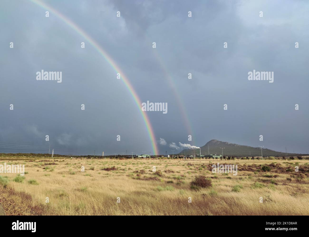 Double arc-en-ciel s'élevant au-dessus d'une zone industrielle. Les arcs-en-ciel primaire et secondaire sont visibles Banque D'Images