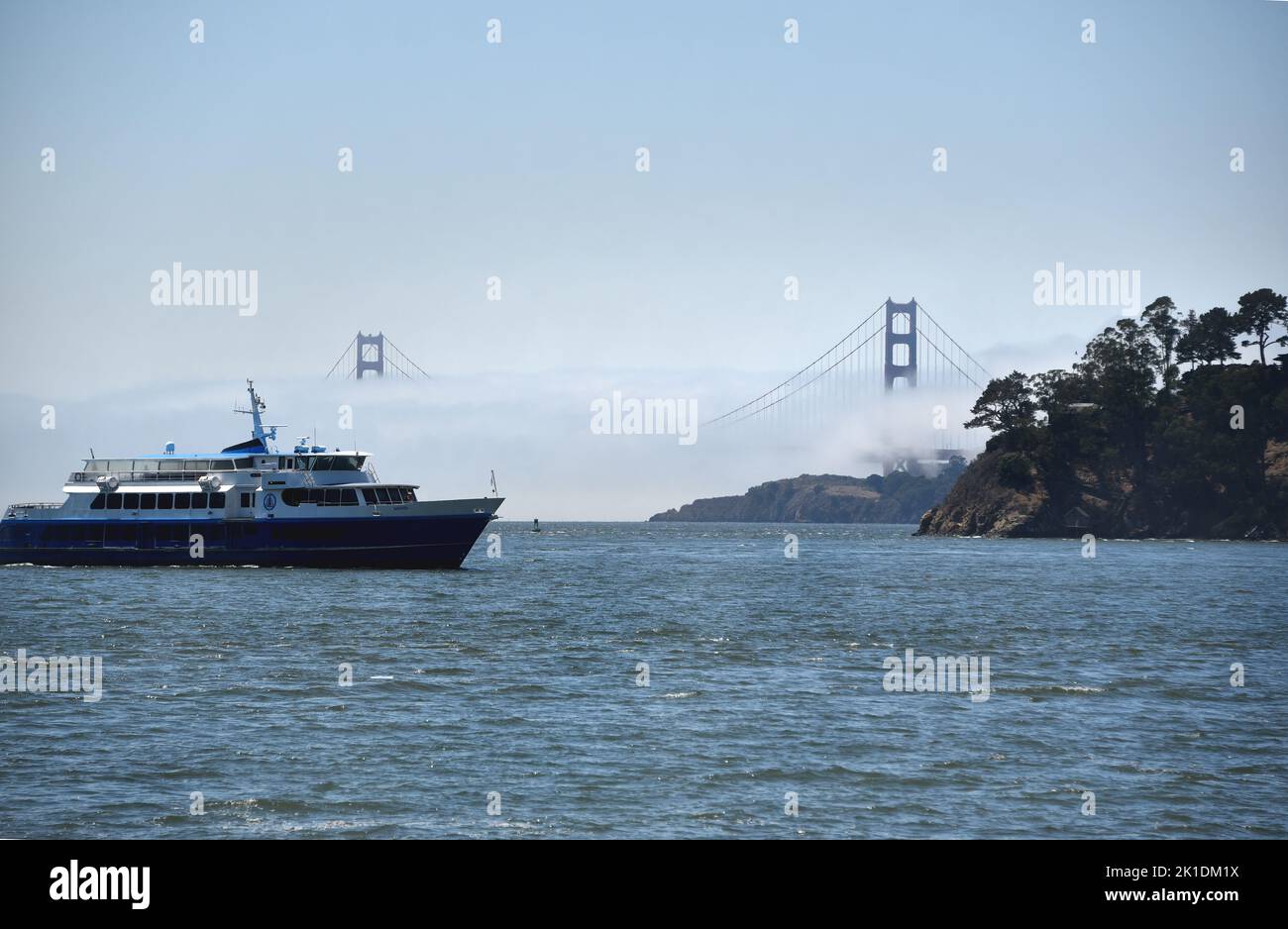 Panorama grand format du pont du Golden Gate couvert de brouillard avec un ferry de San Francisco arrivant à Tiburon en premier plan. Banque D'Images