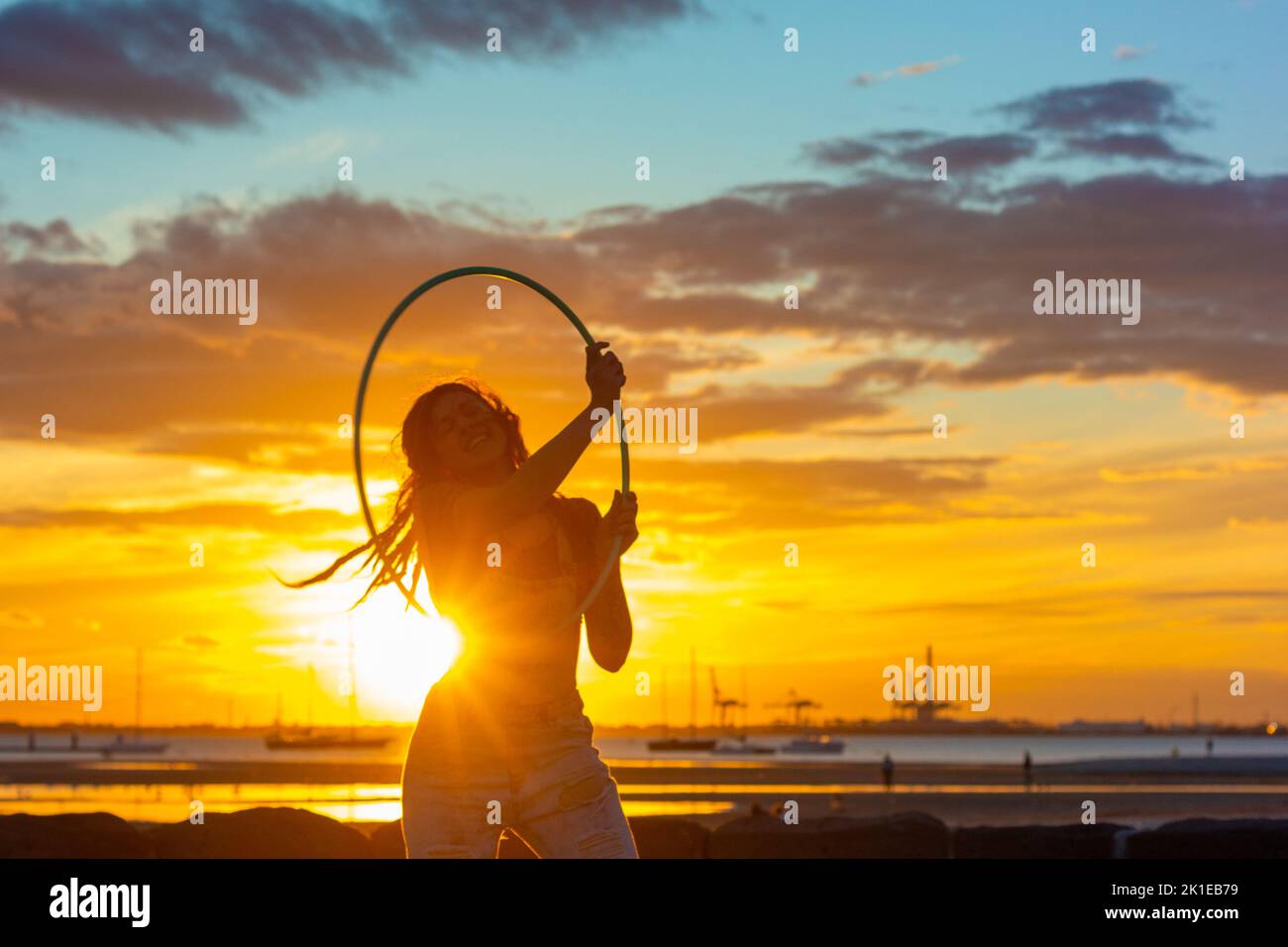 Jeune femme pratiquant avec son cerceau sur l'estran de St Kilda. Banque D'Images