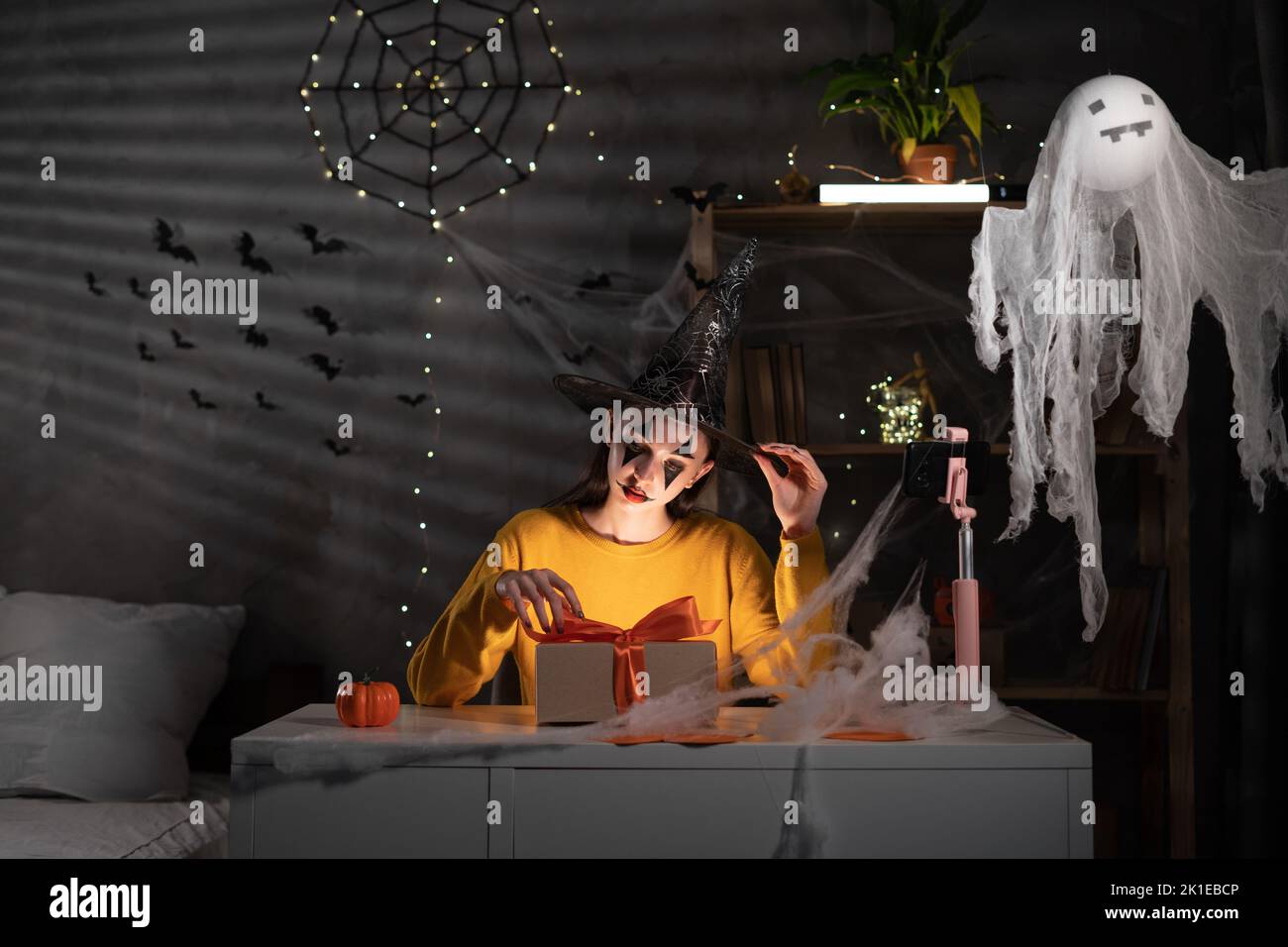 Démarrage petite entreprise entrepreneur ou fille freelance dans Halloween maquillage de prendre l'ordre vidéo en ligne appel en utilisant le smartphone. Emballage de marketing en ligne Banque D'Images