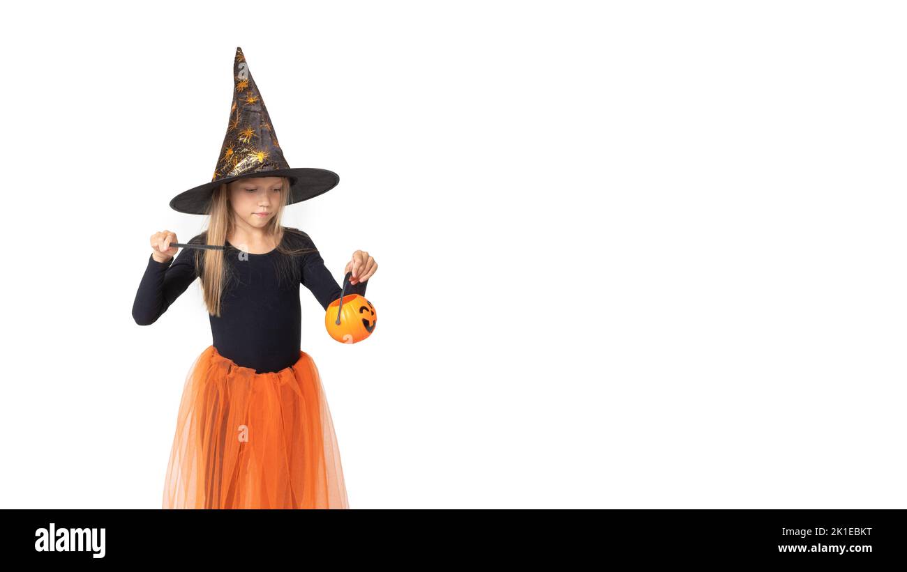 Halloween pour enfants. Une jolie petite fille dans un costume de sorcière, un chapeau, tenant la lanterne de Jack, conjeurrant sur un fond blanc, espace de copie. La petite sorce Banque D'Images