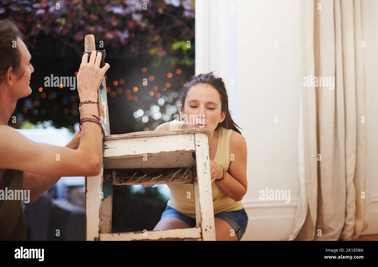 Le restaurer à sa gloire passée. Une jeune femme sablant une chaise ancienne. Banque D'Images