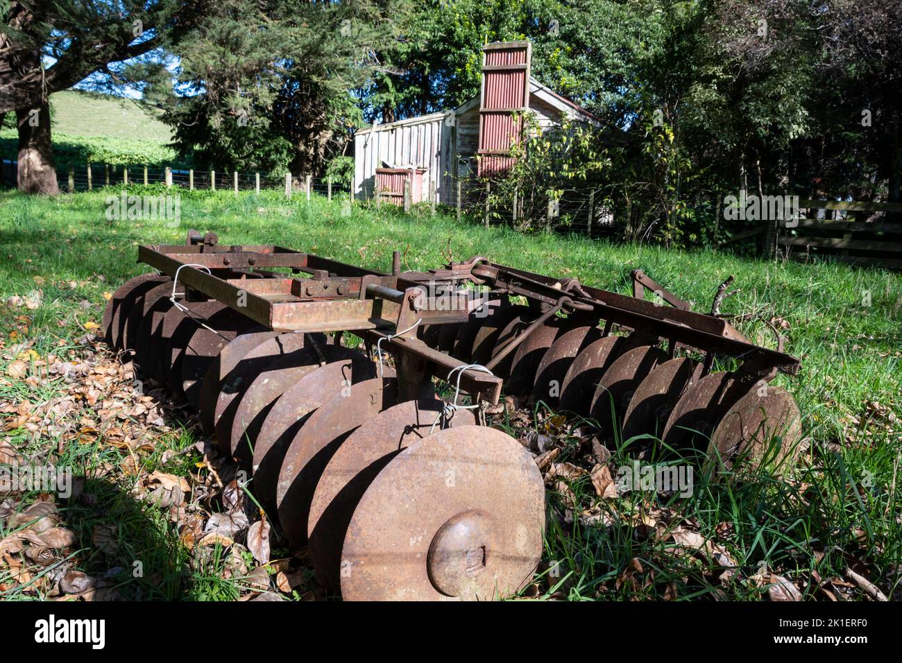 Ancienne machine agricole, une herse à disques, devant le cottage abandonné, Pohangina Valley, Manawatu, Île du Nord, Nouvelle-Zélande Banque D'Images