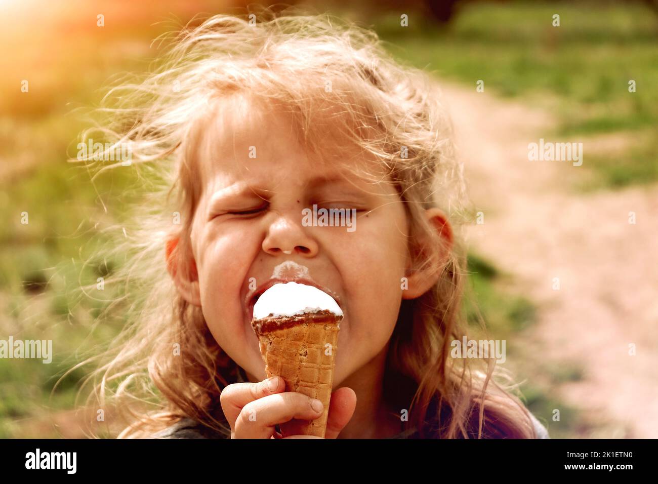 Petite fille drôle mange de la crème glacée. Copier l'espace. Mignon enfant gai dehors. Banque D'Images
