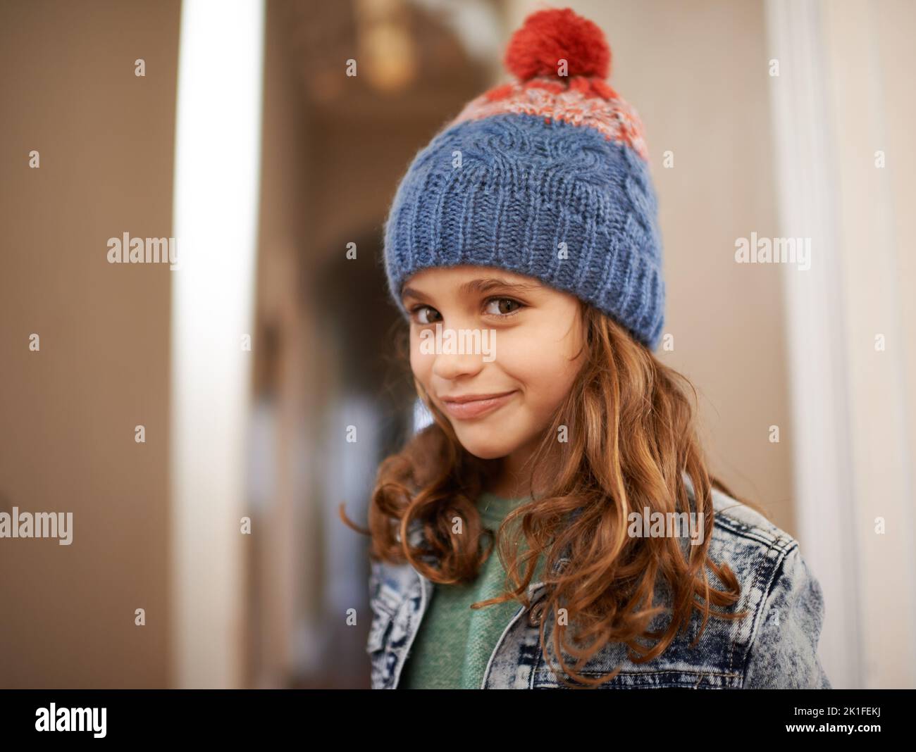 Mordre est mon deuxième prénom. Une adorable petite fille posant avec un chapeau d'hiver tricoté avec un sourire espiègle à l'intérieur Banque D'Images