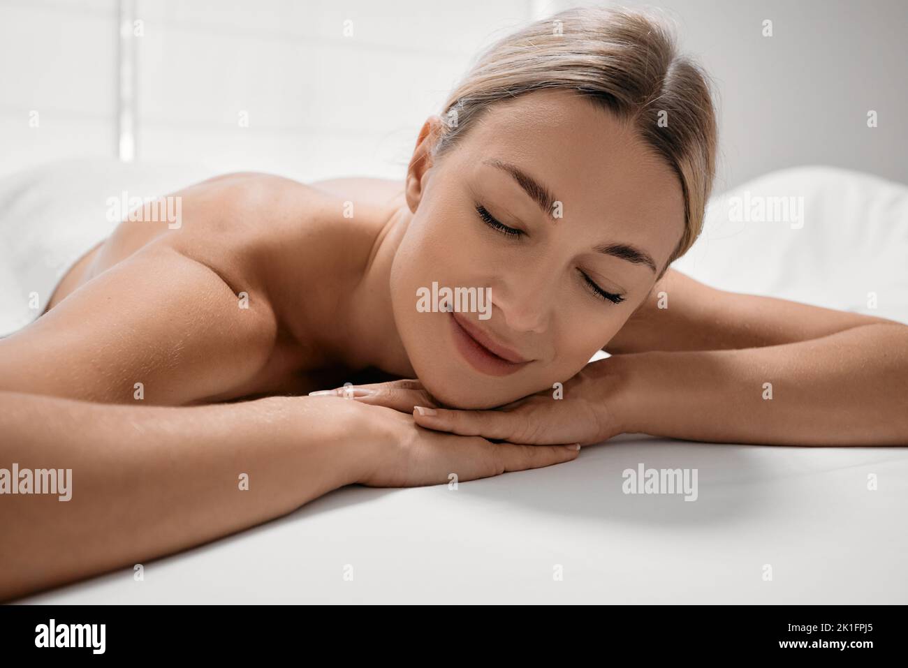 La jolie femme aux yeux fermés se détend sur une table de massage après des massages et des soins spa Banque D'Images