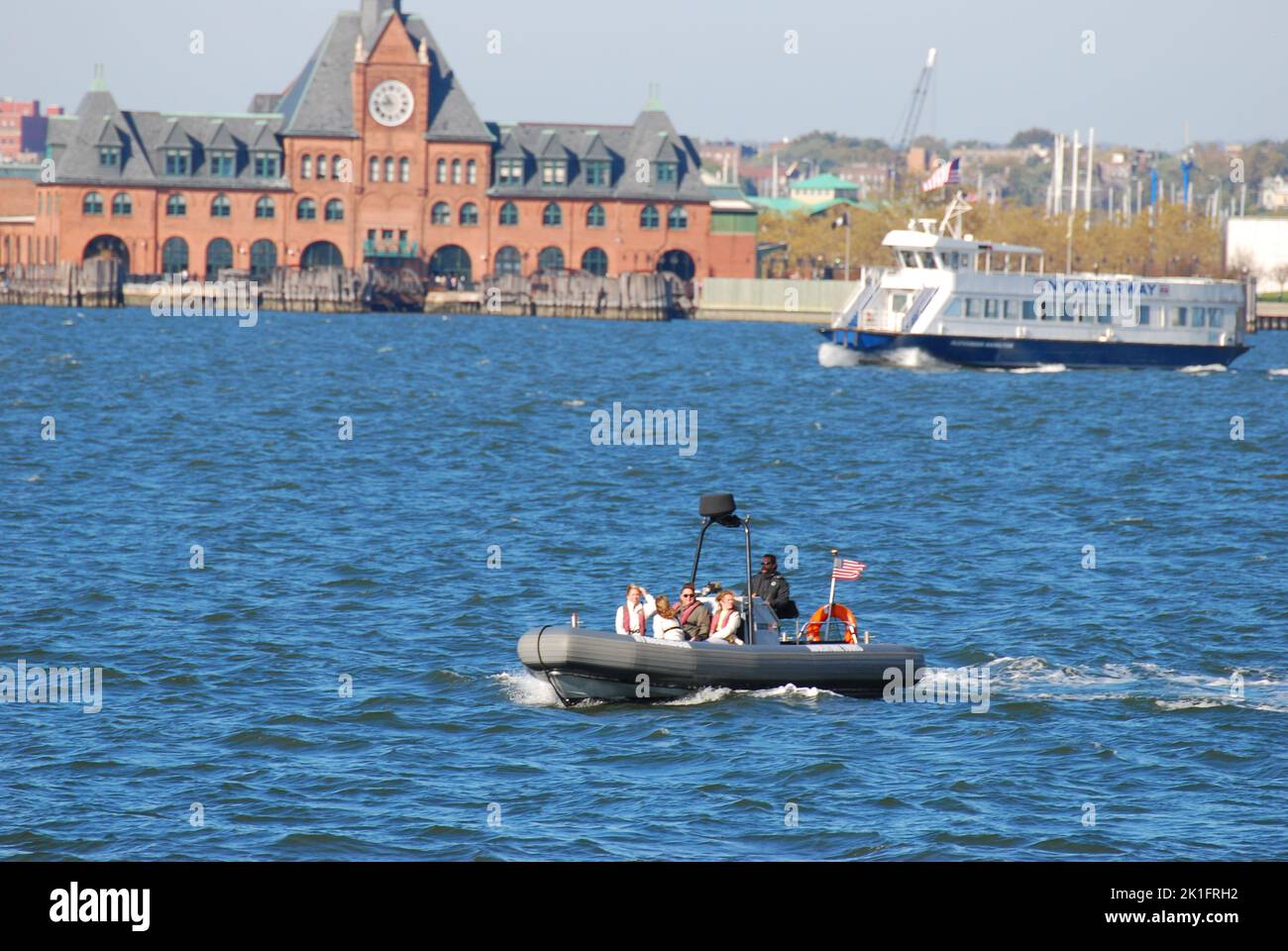 Un petit bateau gonflable sur le fleuve Hudson en face d'Ellis Island à New York, États-Unis Banque D'Images