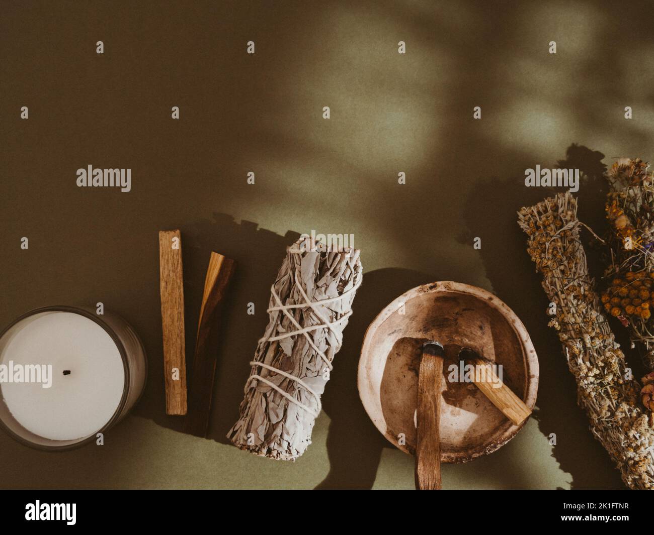 Articles pour le nettoyage spirituel - ensemble de fleurs et de sauge, bâtonnets d'encens de palo santo, bougie blanche sur fond vert. Vue de dessus. Copier l'espace Banque D'Images