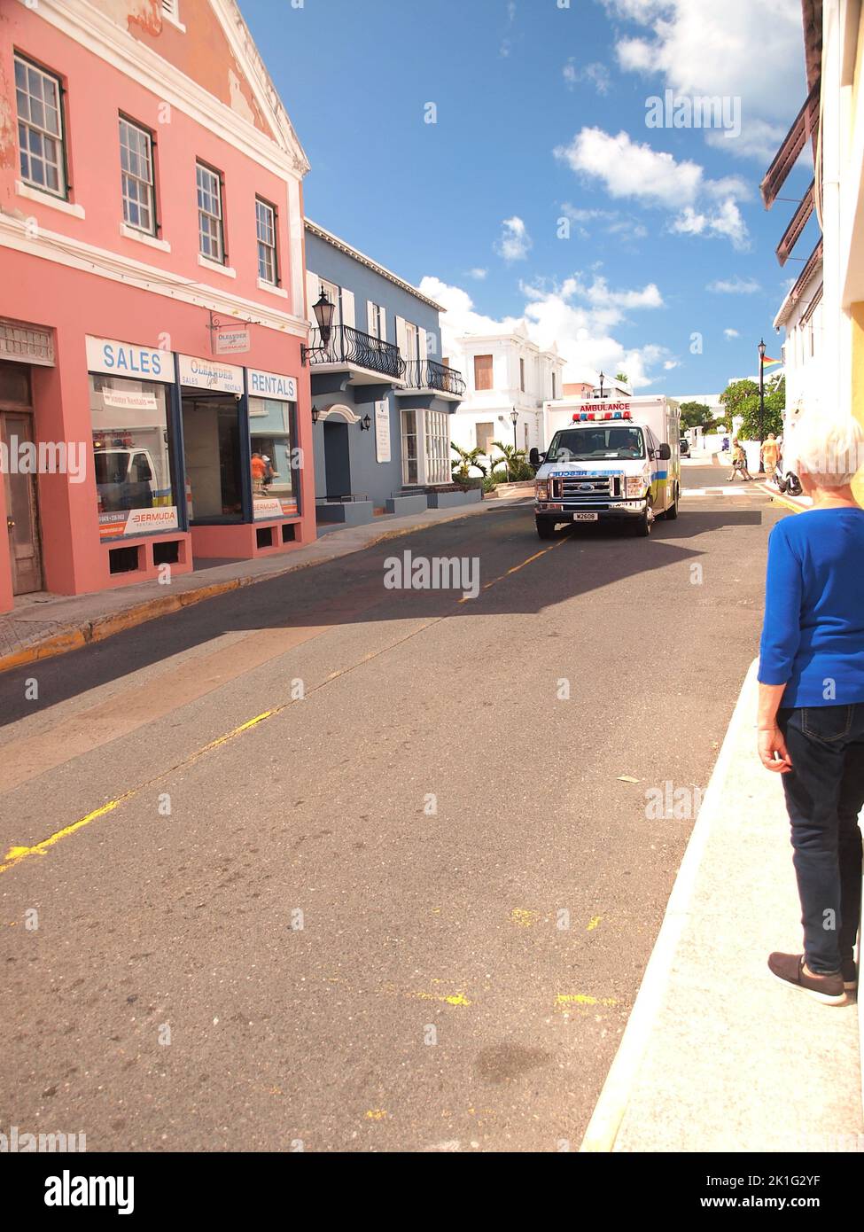 Femme regarde comme Bermuda Fire Rescue ambulance vitesse est sur la rue York à St. Georges Bermudes. Banque D'Images