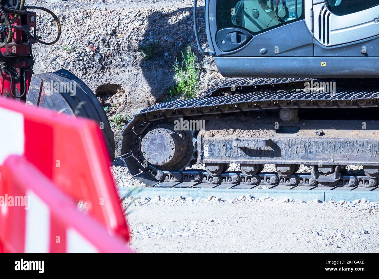 Grue noire sur un chantier de construction en gravier avec un panneau rouge Banque D'Images