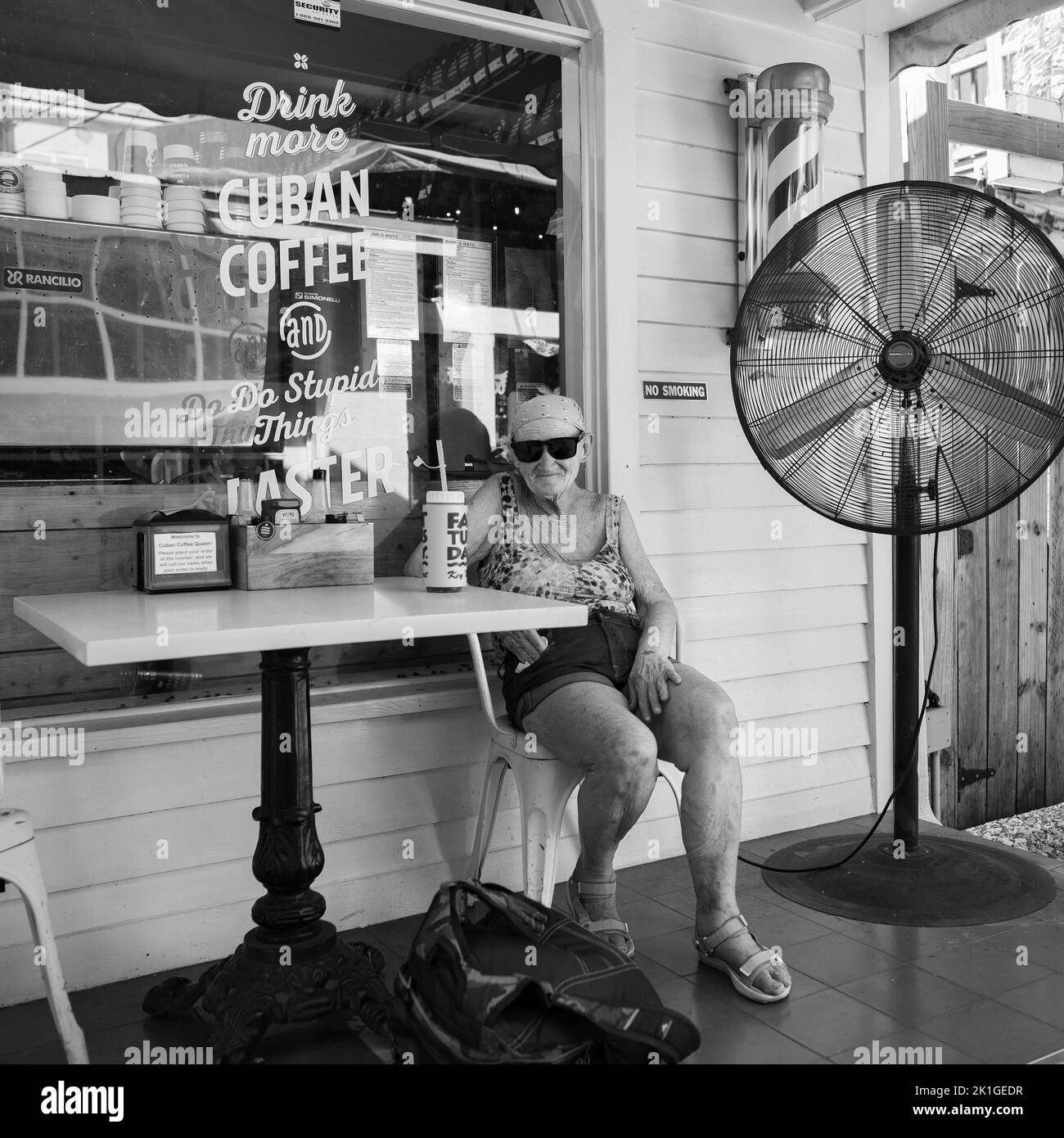 Photo en niveaux de gris d'une femme âgée assise dans un café, Key West, Floride, États-Unis Banque D'Images