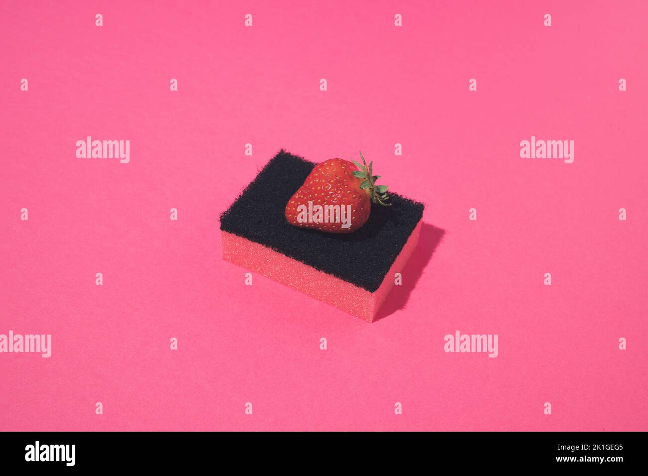 Éponge rose avec fraise fraîche sur le dessus. Concept minimal. Banque D'Images