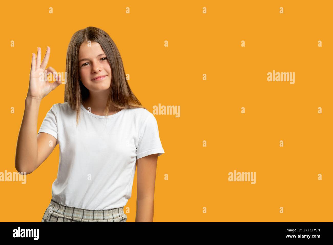 Enfant satisfait. Contexte publicitaire. Le choix parfait. Signature d'approbation. Portrait de gai heureux fille en blanc montrant OK geste souriant isolé o Banque D'Images