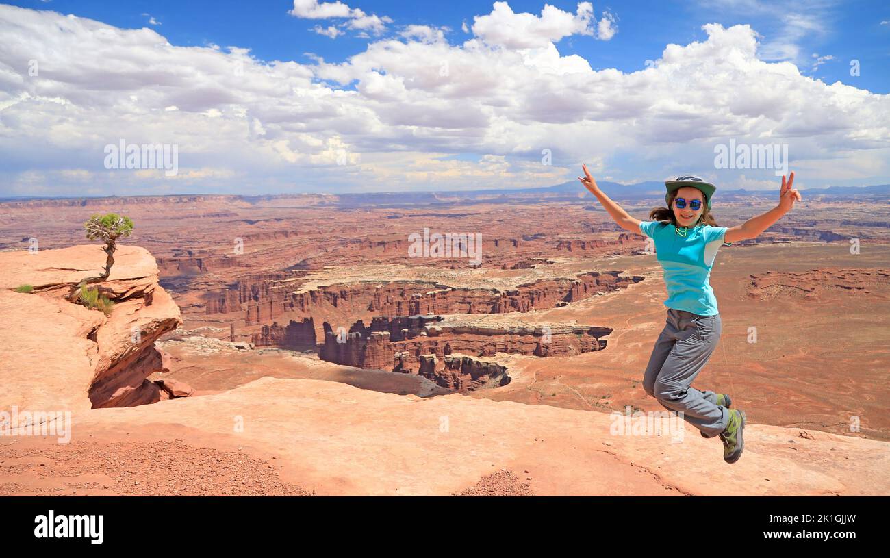 Une jeune fille de touristes bondissant heureux dans le parc national de Canyonlands, Utah, États-Unis Banque D'Images