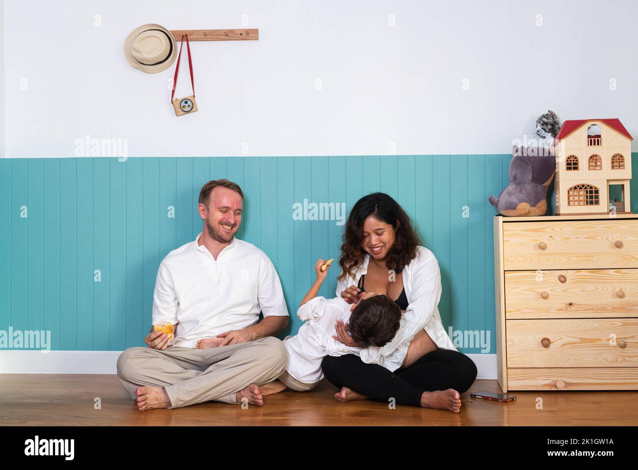 Photo de jeune couple gai positif souriant femme enceinte et mari avec leur fils à la maison Banque D'Images