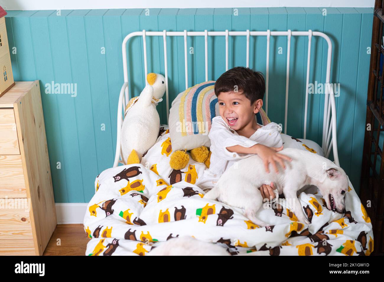 Jeune garçon mignon se reposant sur son lit tout en jouant avec son chien Russell Terrier plan horizontal Banque D'Images