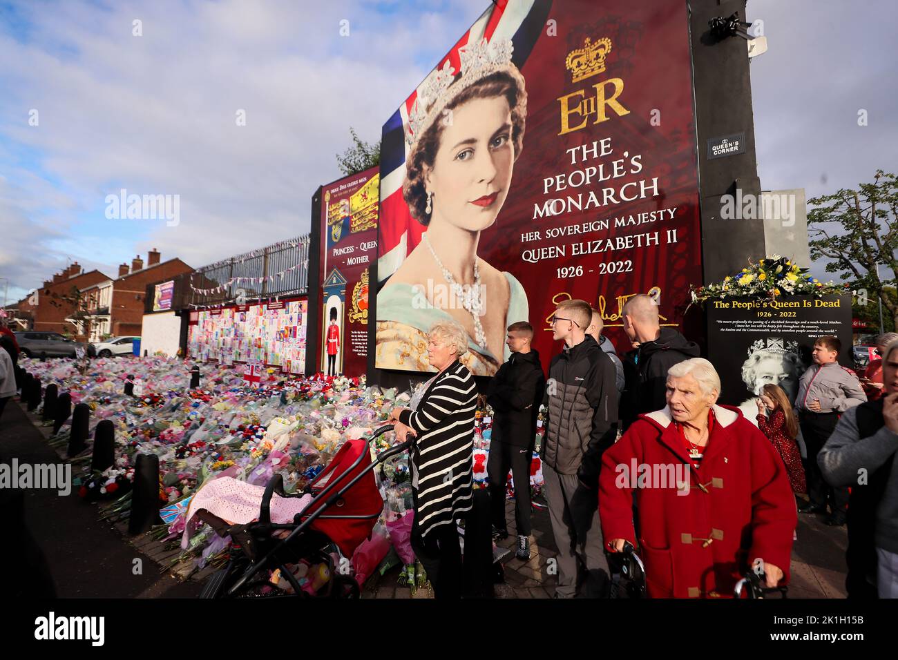 Les gens labouent des fleurs à une fresque représentant la reine Elizabeth II sur la route Shankill à Belfast après le décès du monarque britannique. Banque D'Images