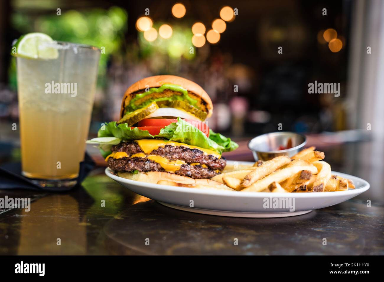 cheeseburger avec deux viandes, des cornichons et des frites sur un bar Banque D'Images