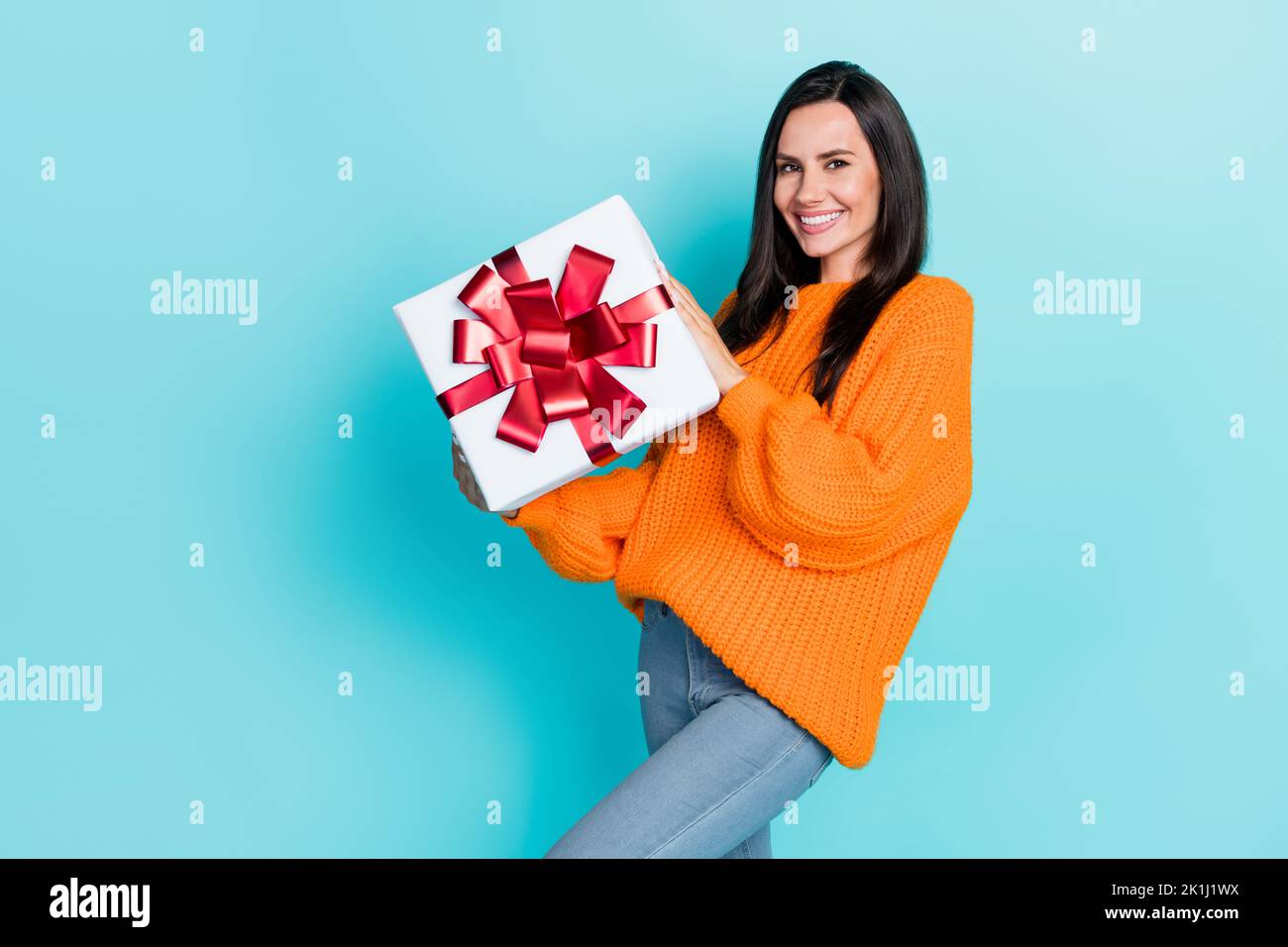 Photo de la belle femme bras positif tenir boîte-cadeau sourire en terre cuite isolé sur fond de couleur bleu-vert Banque D'Images