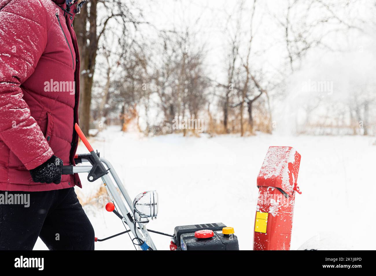 Détail de la souffleuse à neige rouge portable alimentée par l'essence en action. Homme à l'extérieur utilisant une souffleuse à neige après une tempête de neige. Déneigement, assistant de fraise en hiver. Guy soufflant de la neige pendant le blizzard Banque D'Images