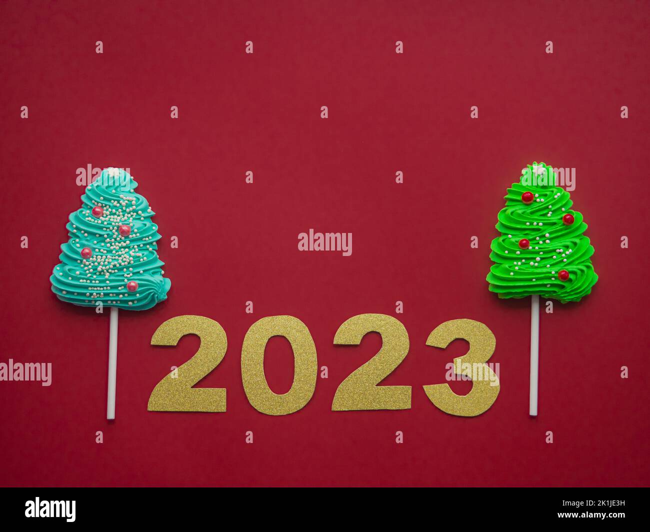 2023 et des bonbons verts et bleus sous forme d'arbre de Noël sur fond rouge Banque D'Images