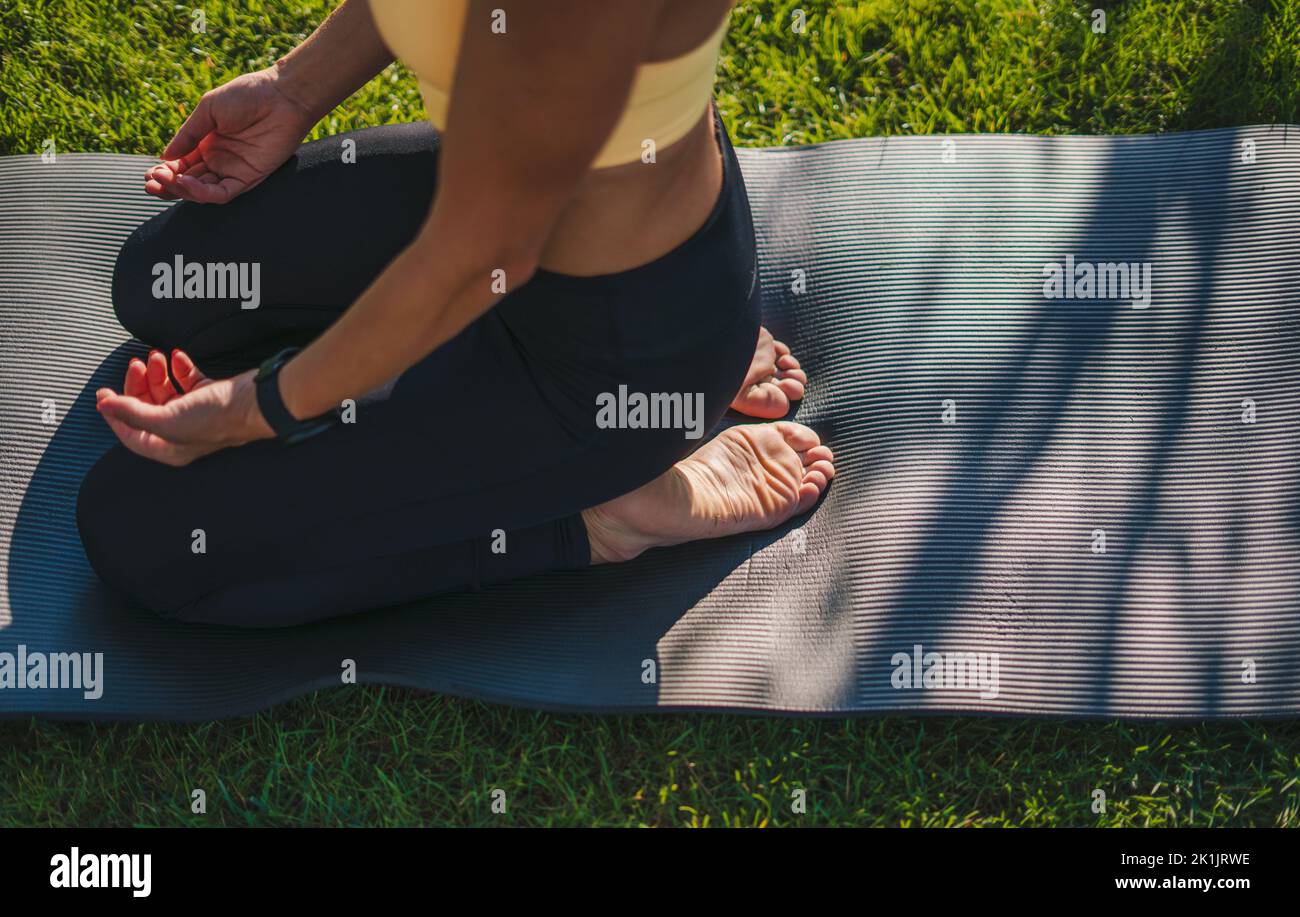 Vue de dessus d'une femme s'agenouillant sur un tapis de yoga pratiquant des exercices de méditation. Entraînement sur le tapis de yoga à l'extérieur, profiter d'un mode de vie sain, gros plan Banque D'Images
