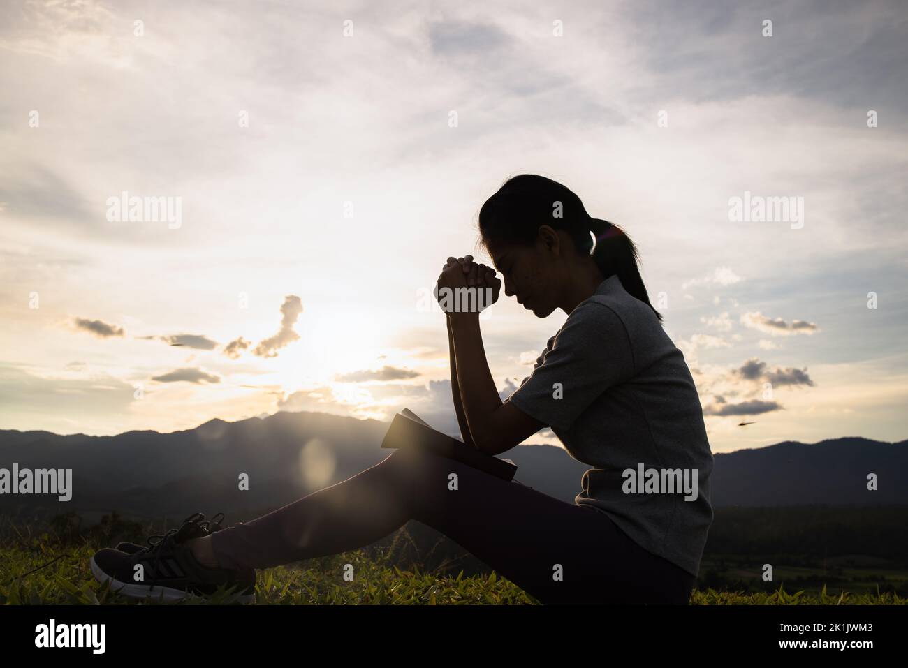Silhouette de la femme chrétienne priant le culte au coucher du soleil. Le concept de religion chrétienne de fond. Mains dans la prière. Adorez dieu avec le concept de religion. Banque D'Images
