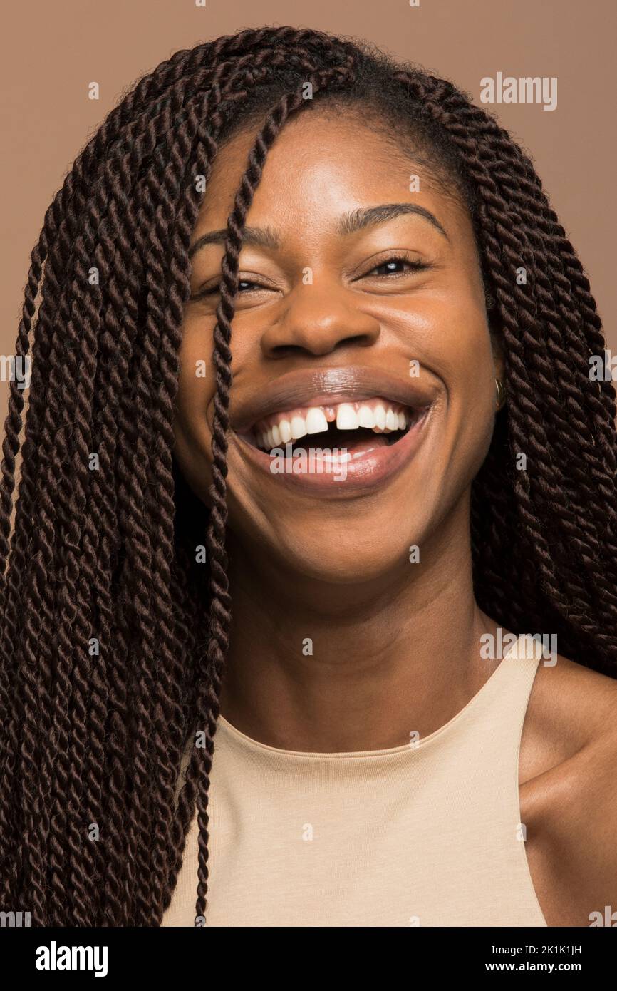 Portrait d'une femme heureuse avec de longues tresses noires riant Banque D'Images