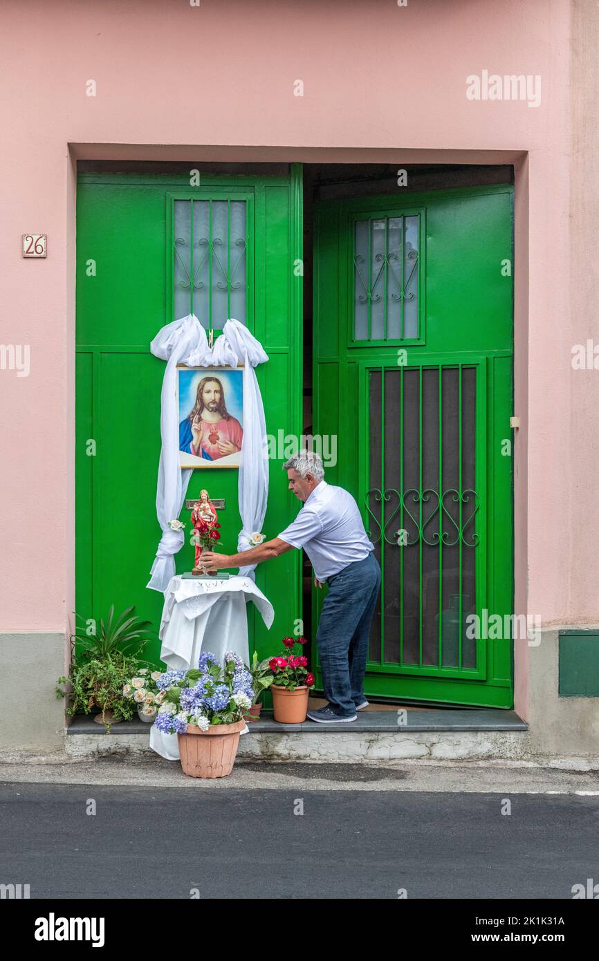 Dans le petit village sicilien de Fornazzo, un homme prépare un sanctuaire religieux à l'extérieur de sa maison avant la fête annuelle du Sacré-cœur Banque D'Images