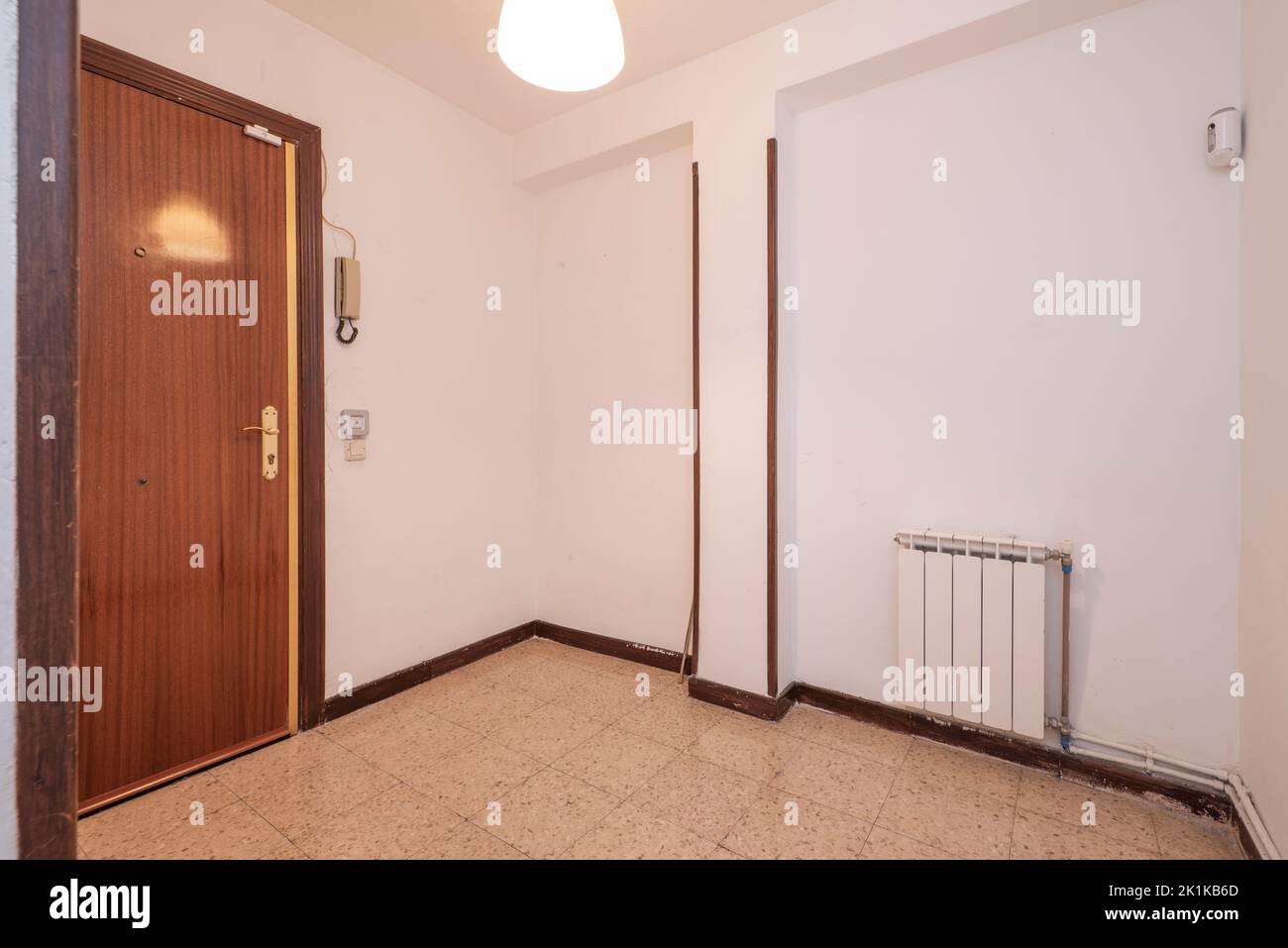 Couloir de distribution avec planchers en terrazzo brun clair, charpente en bois sur les portes et radiateur en aluminium blanc Banque D'Images
