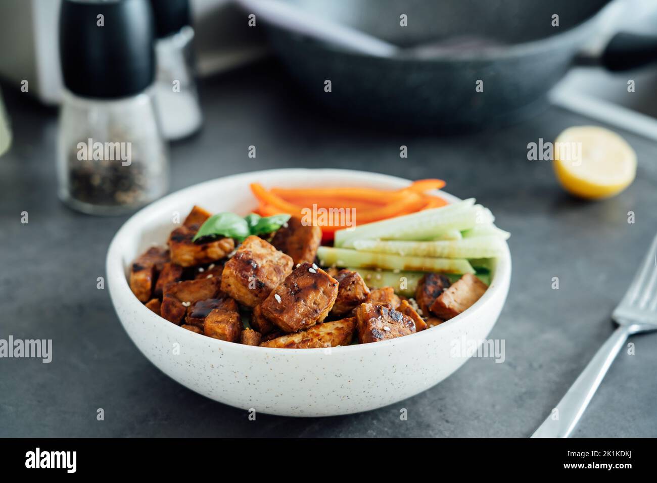 Bol avec tempeh rôti à base de graines de soja fermentées, bâtonnets de légumes frais avec sauce et graines de sésame sur la table. Protéines à base de plantes. Co. En bonne santé Banque D'Images Bol avec tempeh rôti à base de graines de soja fermentées, bâtonnets de légumes frais avec sauce et graines de sésame sur la table. Protéines à base de plantes. Co. En bonne santé Banque D'Images