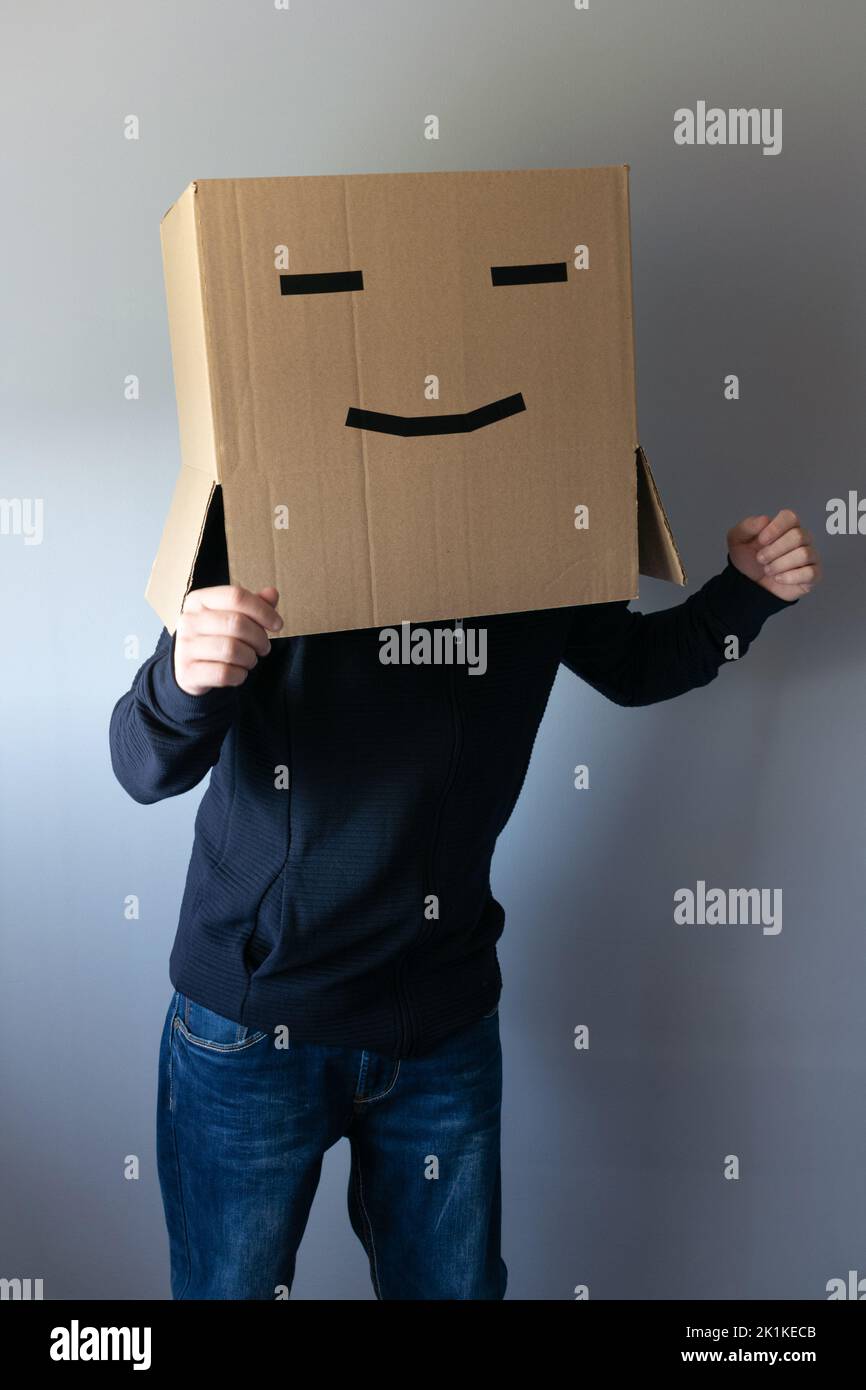 Homme souriant avec une boîte en carton sur sa tête dansant Banque D'Images