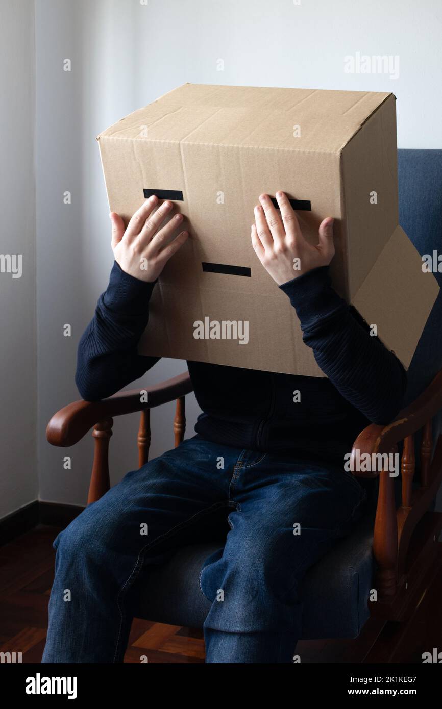 Triste homme avec une boîte en carton sur sa tête couvrant son visage avec ses mains Banque D'Images