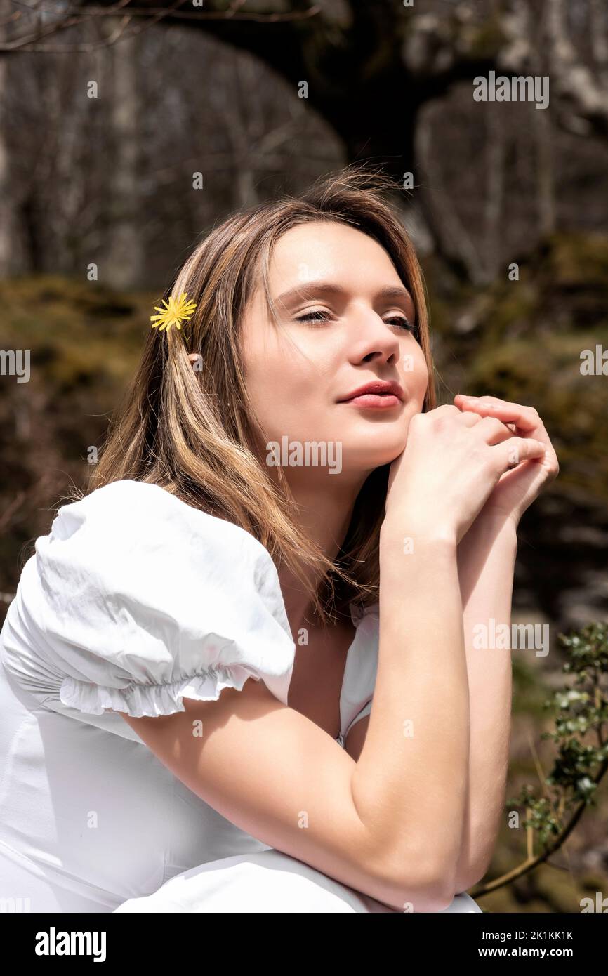 femme en robe blanche assise dans la forêt pensive Banque D'Images