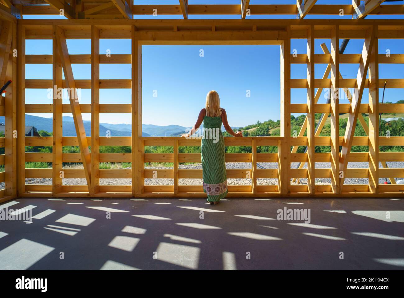 Femme senior sur le site à l'intérieur de construction encadrant rêver de sa nouvelle maison et regardant la vue. Banque D'Images
