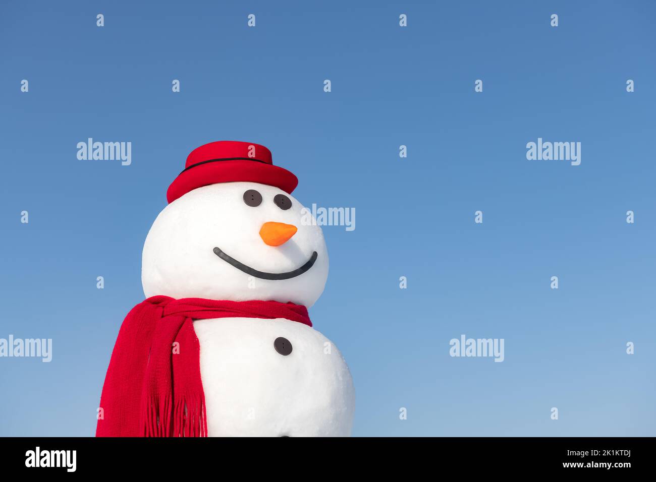 Bonhomme de neige drôle en élégant chapeau rouge et rouge scamf gros plan sur fond bleu ciel Banque D'Images