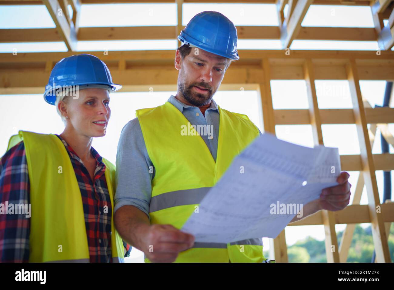 Les ingénieurs de construction ou les architectes avec des plans-plans vérifiant le site de construction écologique de la maison de cadre en bois Banque D'Images