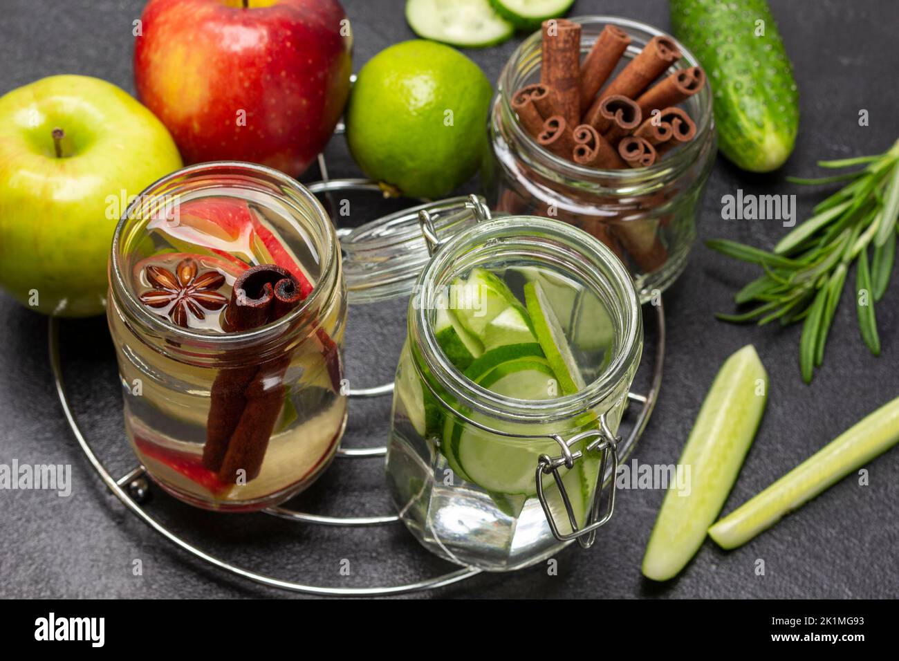 Eau infusée à la cannelle, à la pomme et au concombre dans un pot en verre. Bâtonnets de cannelle dans un pot en verre. Légumes et fruits sur table. Arrière-plan noir. Vue de dessus Banque D'Images