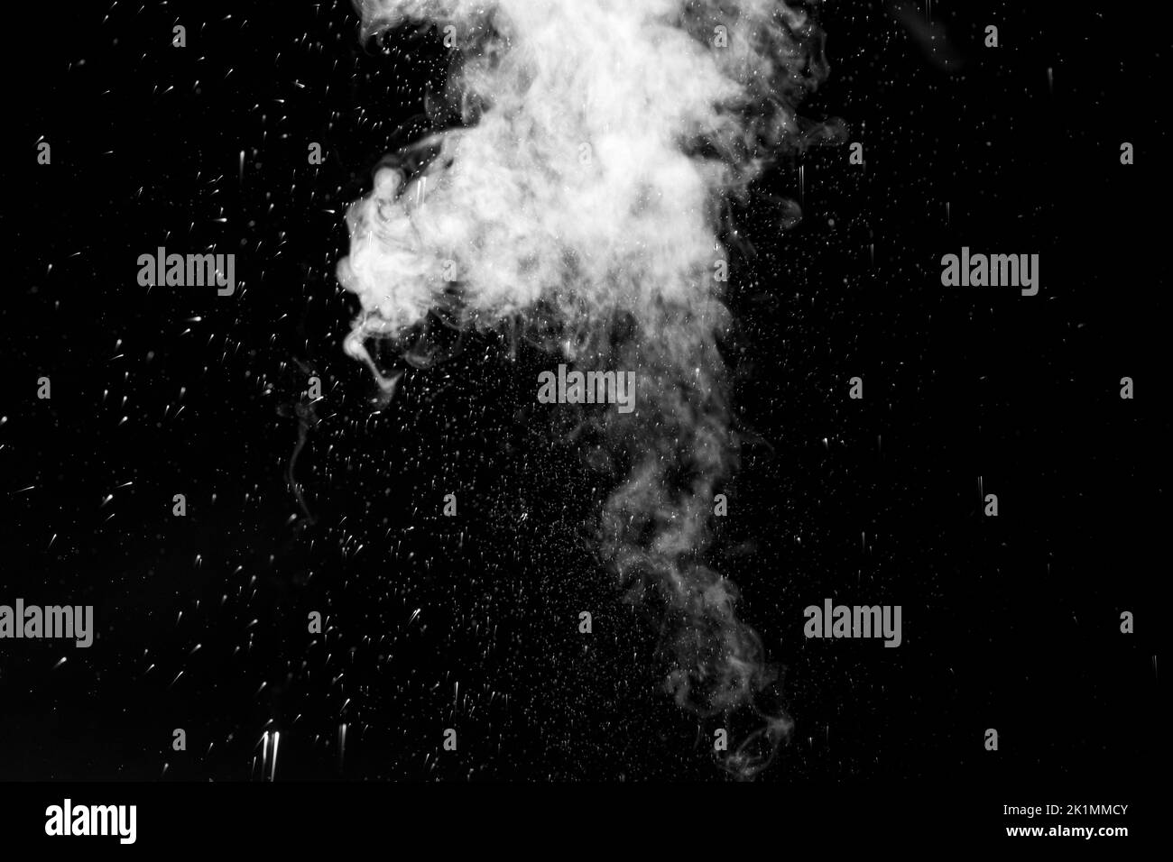 Vapeur blanche bouclés qui s'élève et projection d'eau dans différentes directions isolée sur fond noir. Évaporation du liquide et du condensateur Banque D'Images
