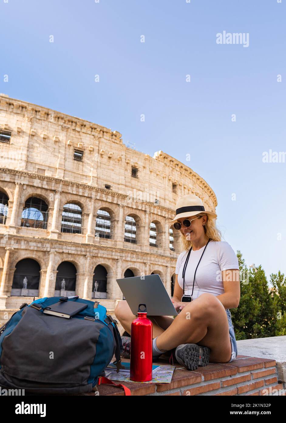 Jeune femme travaille assis avec son ordinateur heureusement au milieu de la ville, nomade numérique, espace de copie, plan vertical Banque D'Images