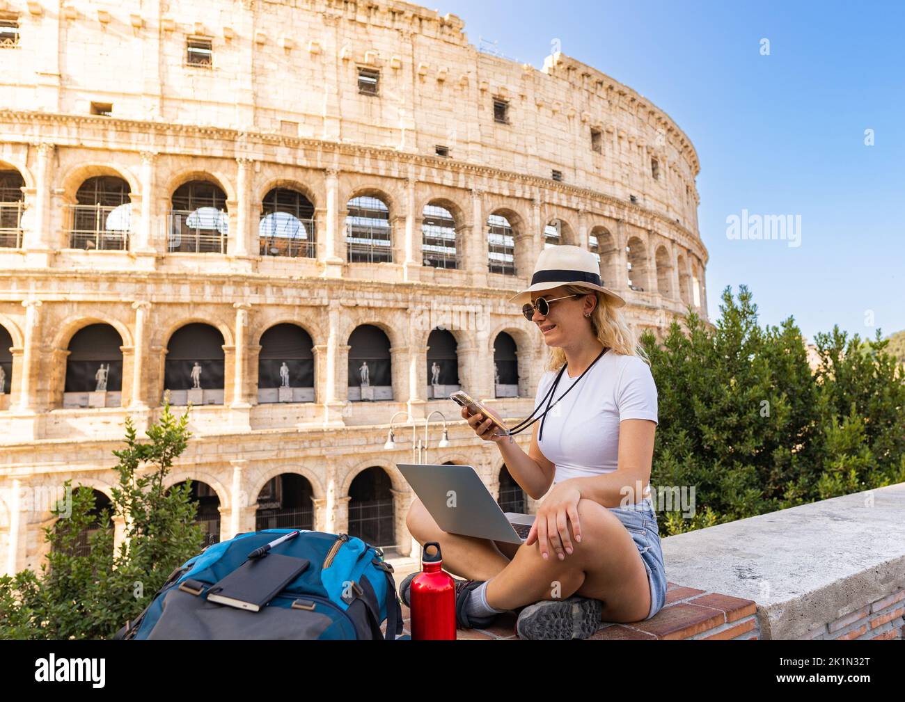Jeune femme travaille assis avec son ordinateur et regarde son smartphone heureusement au milieu de la ville, nomade numérique, espace de copie Banque D'Images