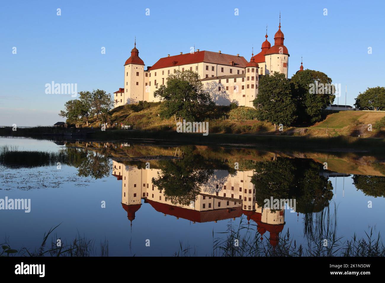 LIDKOPING, SUÈDE, 23 AOÛT 2022 : vue sur le château de Lacko (Läcko Slott) au coucher du soleil, reflétée dans les eaux calmes du lac Vanern. Le château est un très populaire tou Banque D'Images
