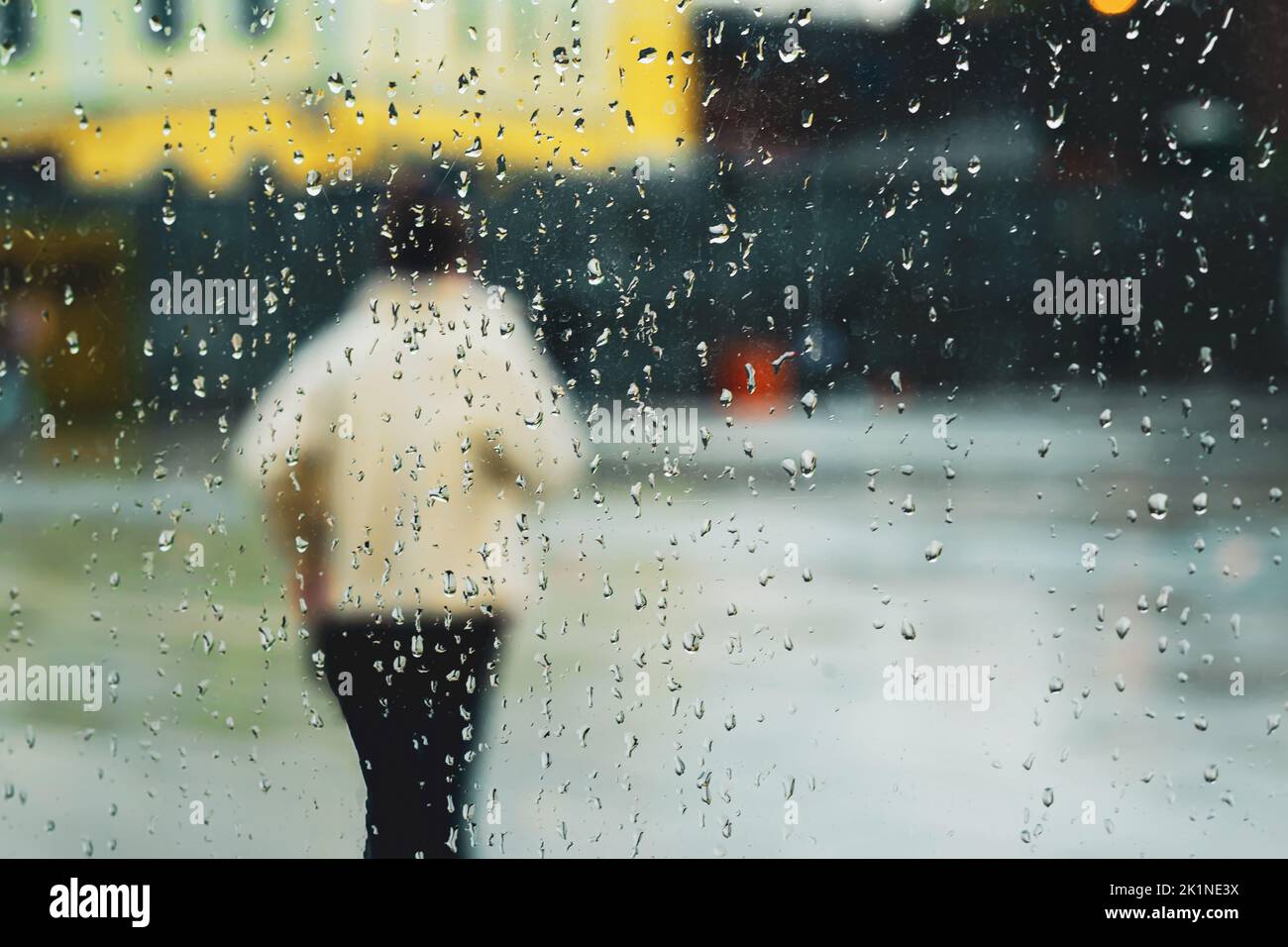 Résumé arrière-plan pluie dans la ville de nuit, silhouette de jeune femme derrière la fenêtre humide à travers les gouttes de pluie sur le verre Banque D'Images