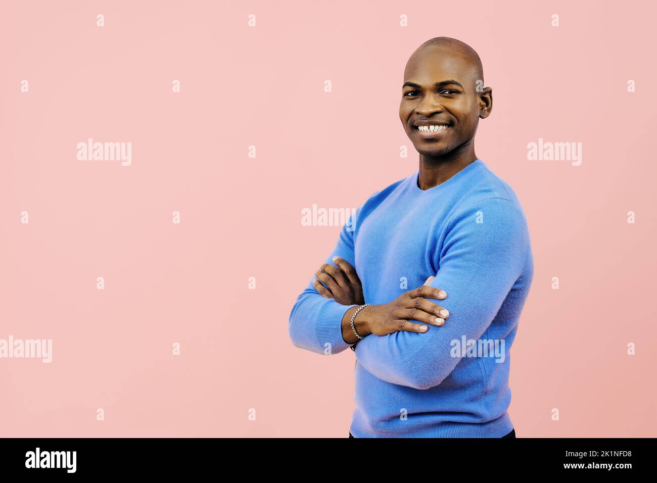 homme souriant avec les bras pliés regardant la caméra à l'intérieur du studio Banque D'Images