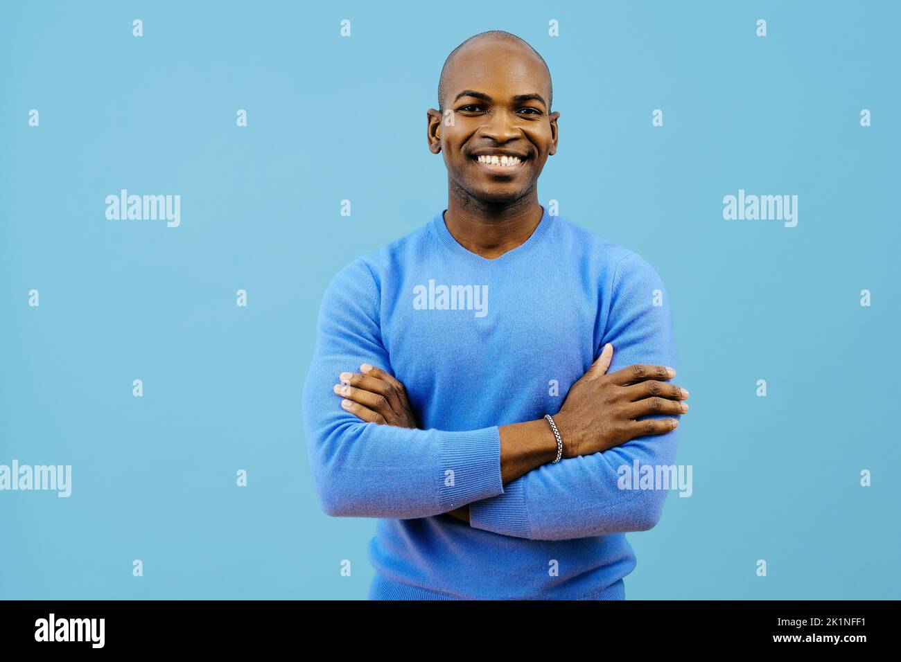 homme souriant avec les bras pliés regardant la caméra à l'intérieur du studio Banque D'Images