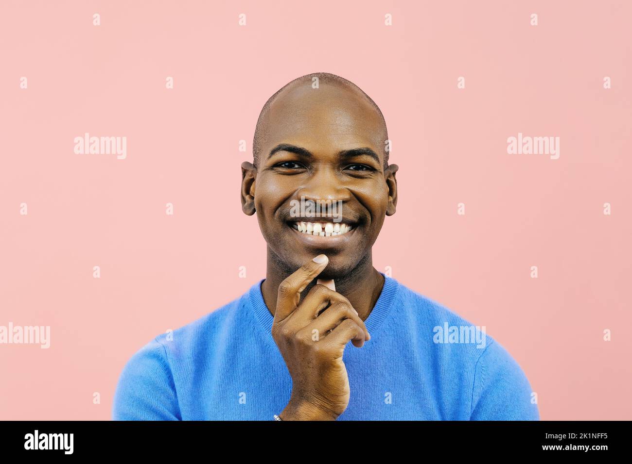 Homme souriant avec la main sur le menton regardant la caméra à l'intérieur studio gros plan Banque D'Images