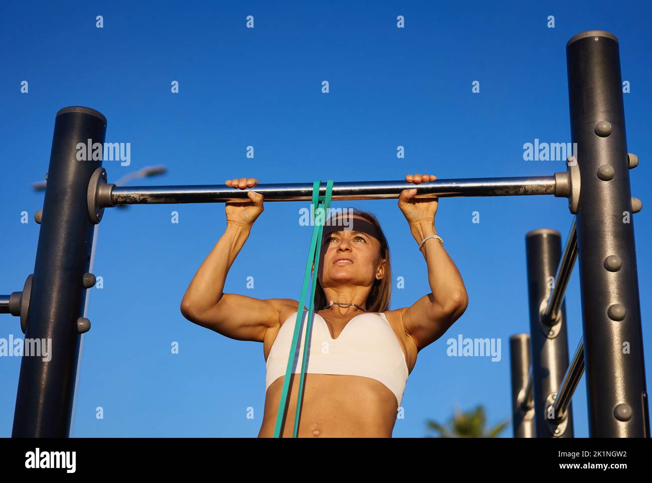 Femme s'exerçant sur le bar horizontal à l'extérieur à l'automne, dans le parc public Banque D'Images